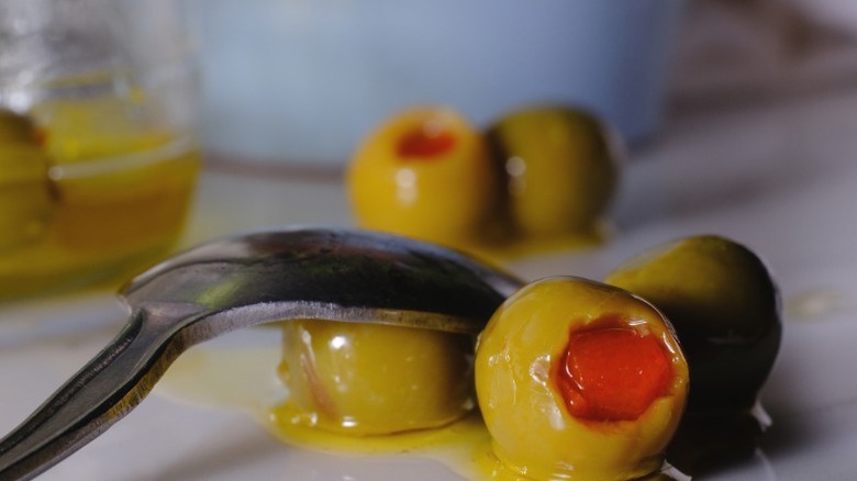 Close-up of pimento stuffed olives on a countertop with a spoon resting on top