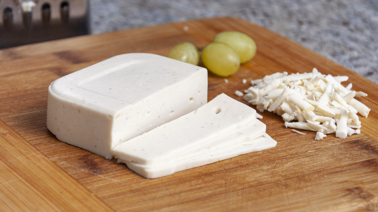 vegan mozzarella cheese on a cutting board with three grapes