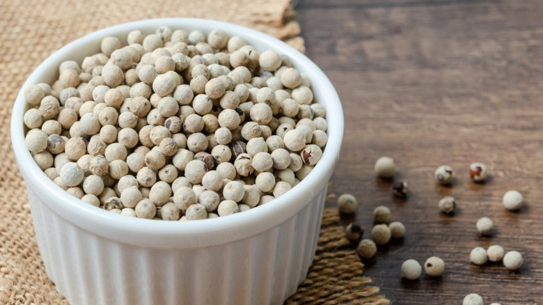 A small bowl filled with white peppercorns.