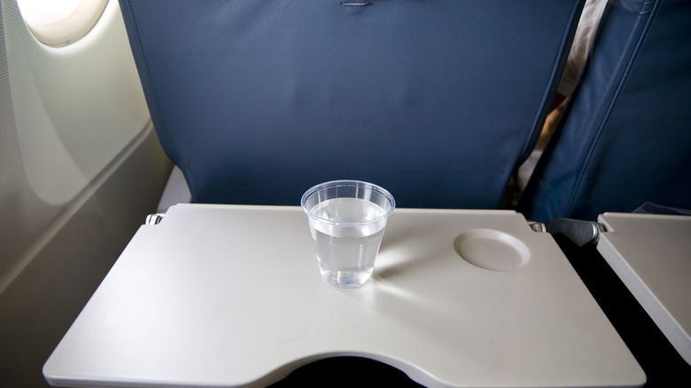 a cup of water on an airplane seat tray