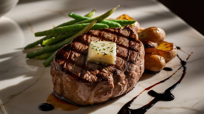 A steak served on a white plate with green beans and potatoes.