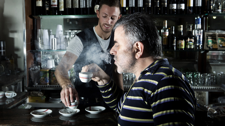 a man standing in an Italian coffee bar enjoying his espresso