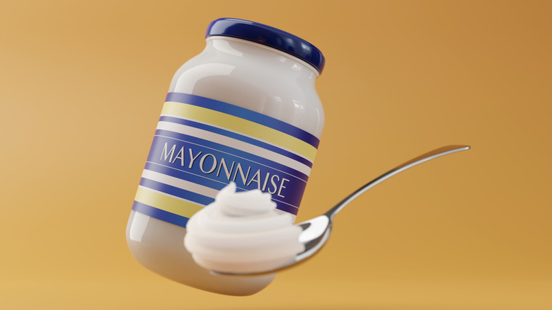 A jar of mayonnaise behind a spoonful of the condiment