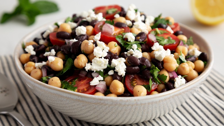 Colorful salad in white bowl with canned beans and feta