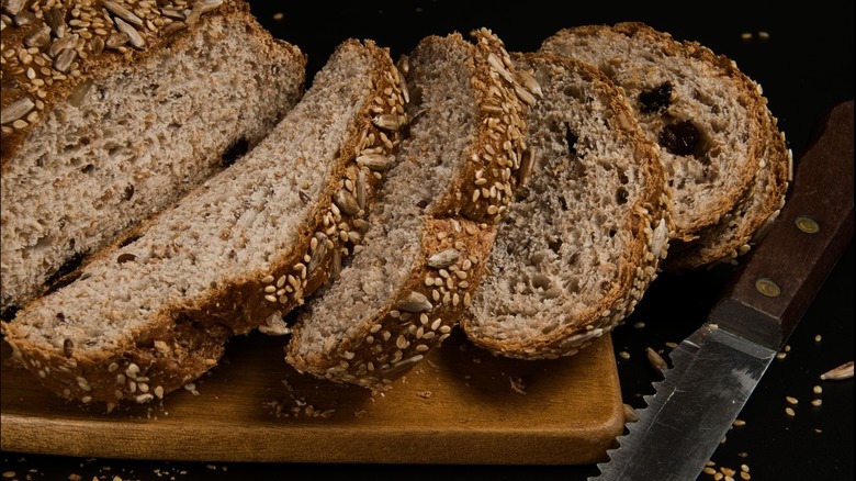 multi-grain bread sliced on cutting board with knife