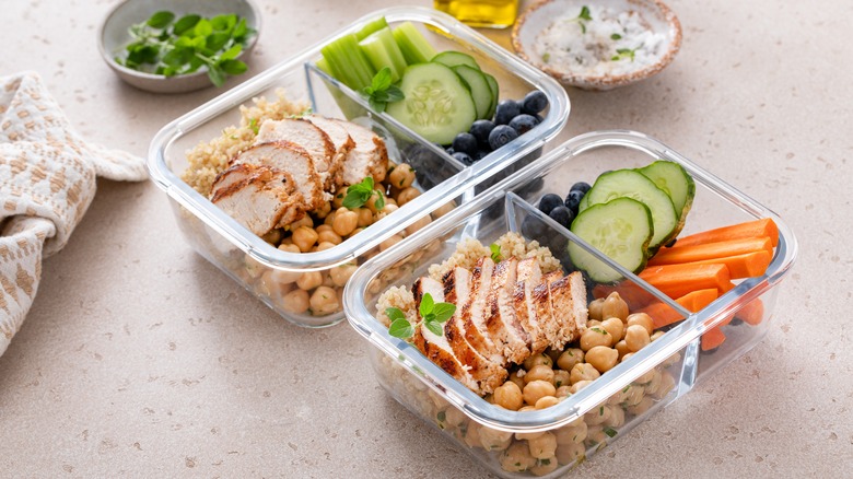 Two lunchboxes filled with cold vegetables, chicken, and chickpeas