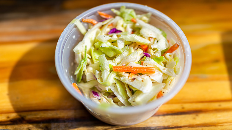 Some coleslaw served in a plastic cup.