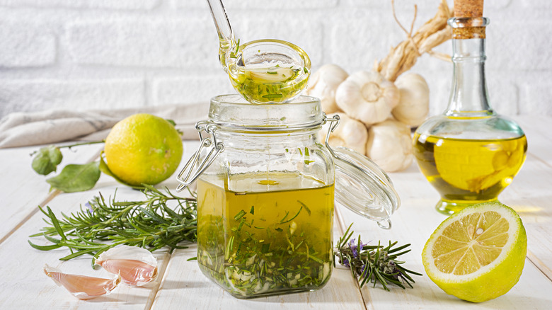 Salad dressing with lemon, olive oil, and herbs inside a jar.