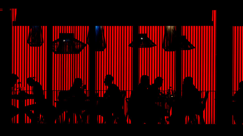 Silhouettes of diners at a red-lit restaurant