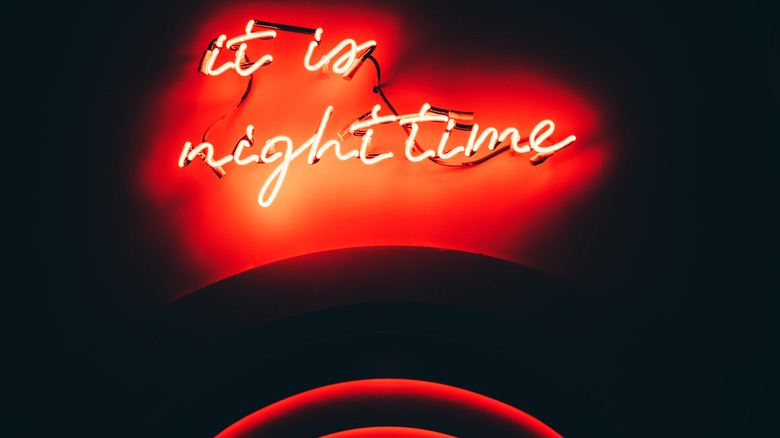 A red neon sign that reads "it is nighttime"