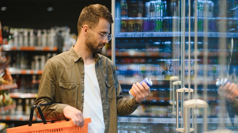 Supermarket shopper looks at a can of beer.