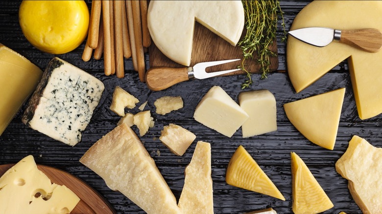 Various hard cheeses cut into wedges and scattered flat on a table