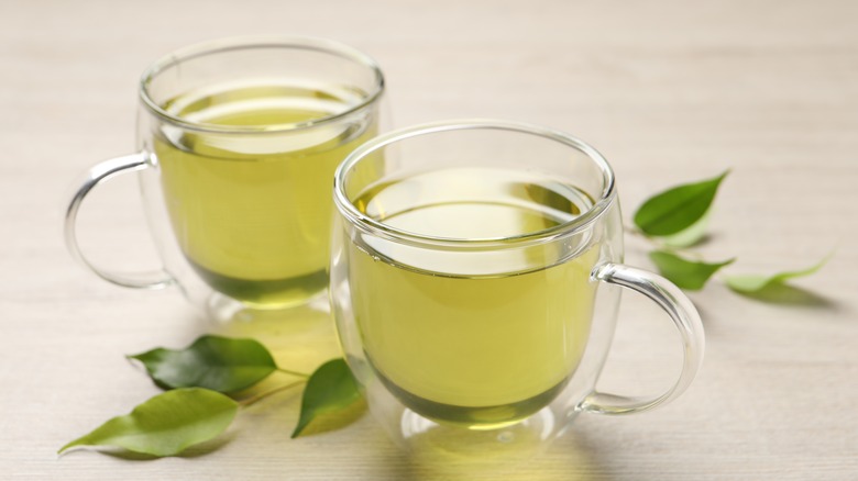 Refreshing green tea in cups with leaves