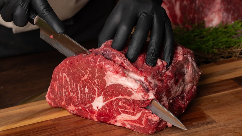 Butcher cutting meat with knife