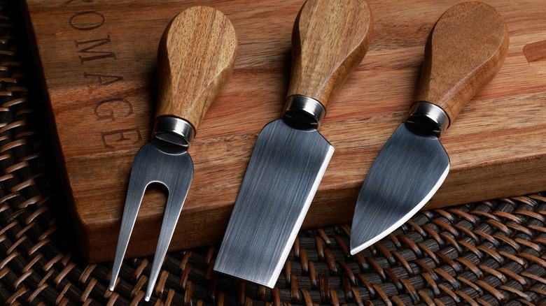 Three types of cheese knives on a wooden block