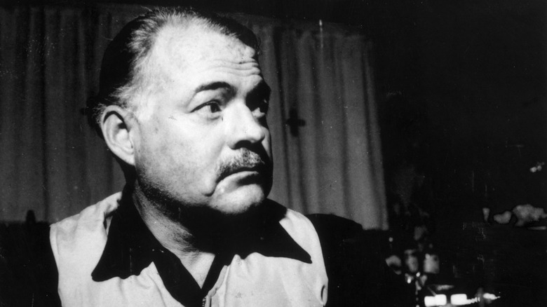 Ernest hemingway sits at a bar with an alcoholic beverage