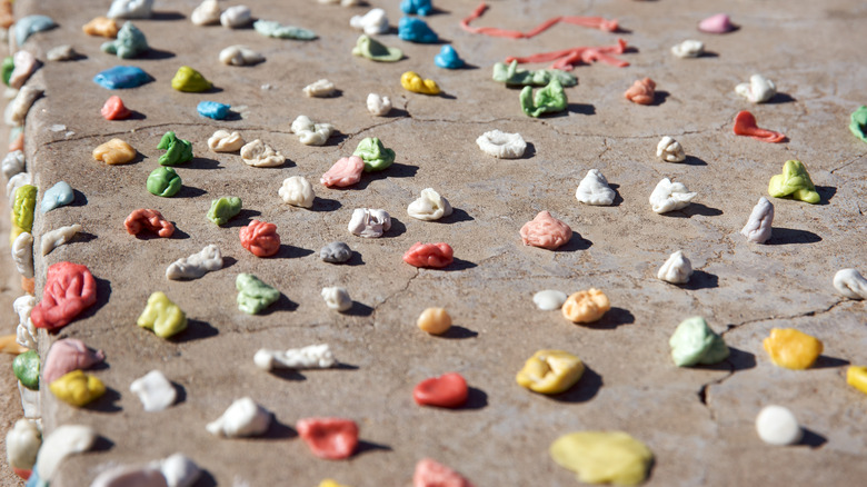 A collection of various colored chewed gum on a sidewalk