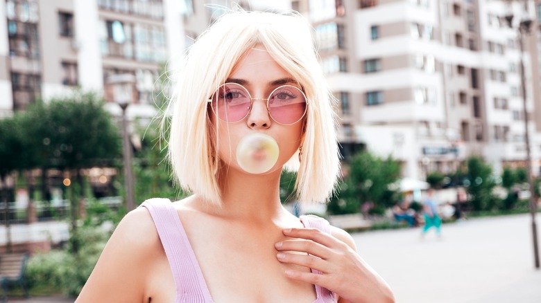 A young woman blowing a pink bubble of bubble gum