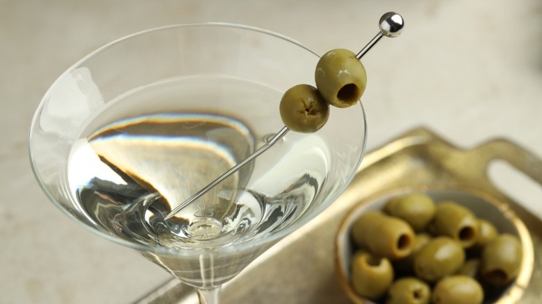 A martini viewed from above, next to a bowl of olives.