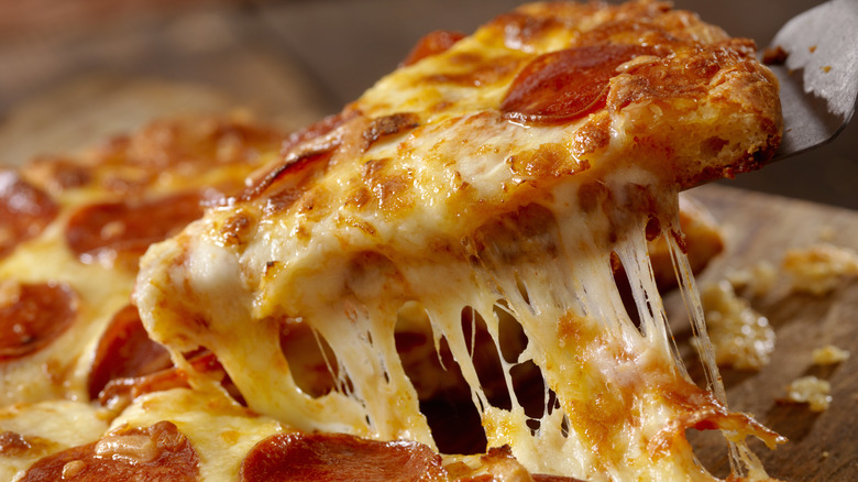 cheesy pizza slice being lifted on a spatula