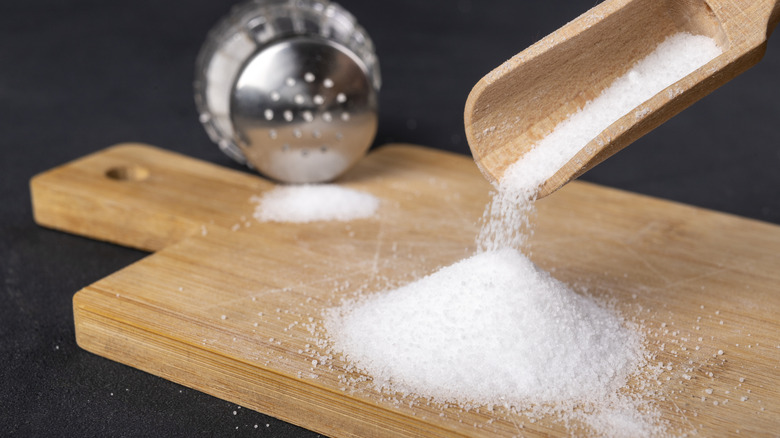 salt being poured onto wooden board and salt shaker