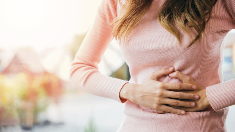 A woman holds her stomach in pain