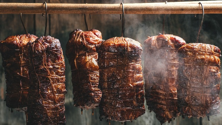 A number of hams hanging up to cure in a smokehouse.