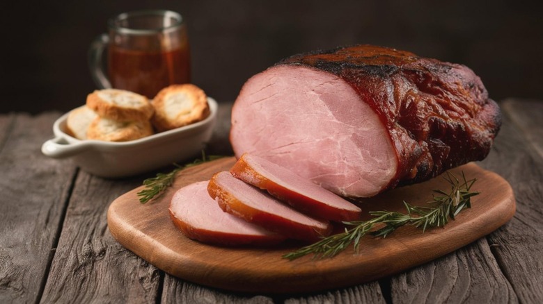 A country ham served on a platter, with biscuits in the background.