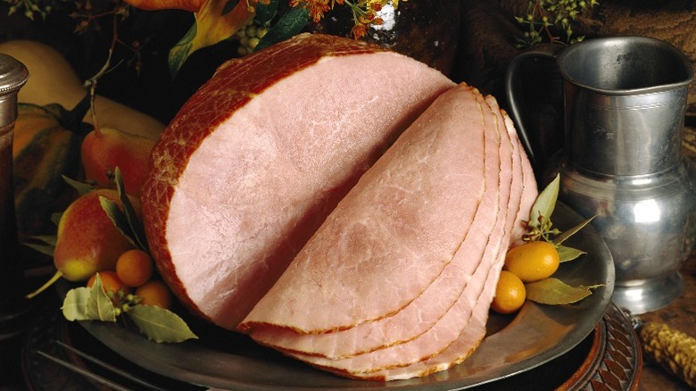 A large ham, sliced on a platter.