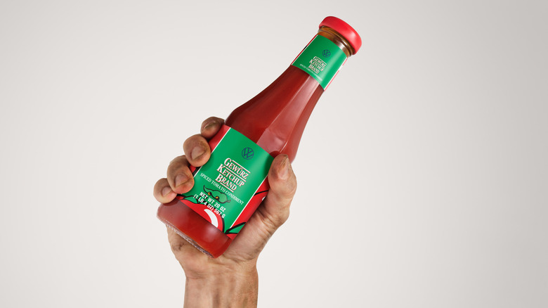 A person holding a bottle of Volkswagen Gewürz Ketchup Brand.