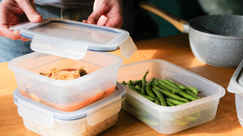 Someone putting the lid onto a plastic container with food inside