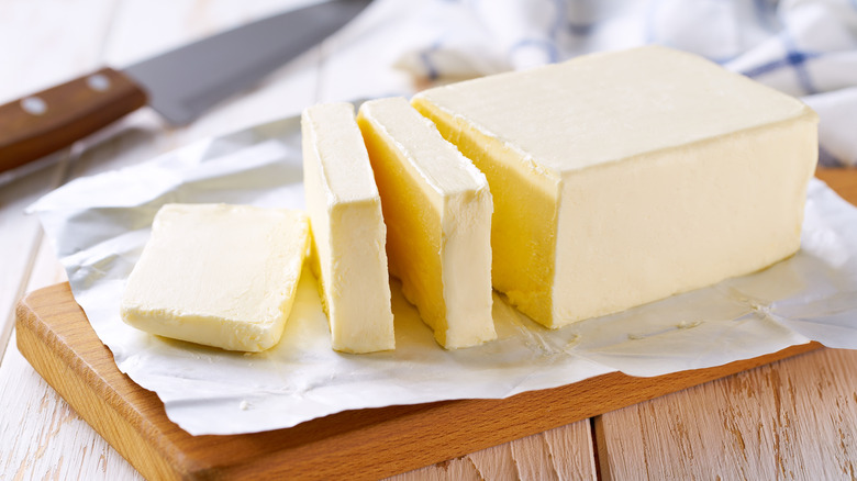 A stick of butter sliced on a wooden board