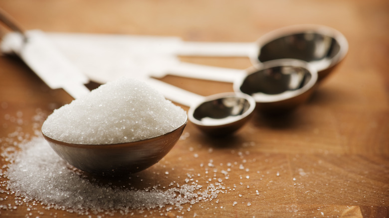 a set of round measuring spoons with a tablespoon of white sugar