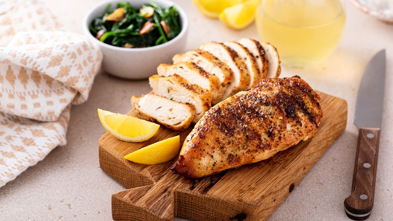 A grilled chicken breast on a wooden cutting board