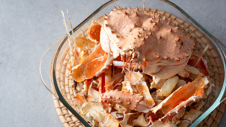 A bowl of crab shells on a wicker mat