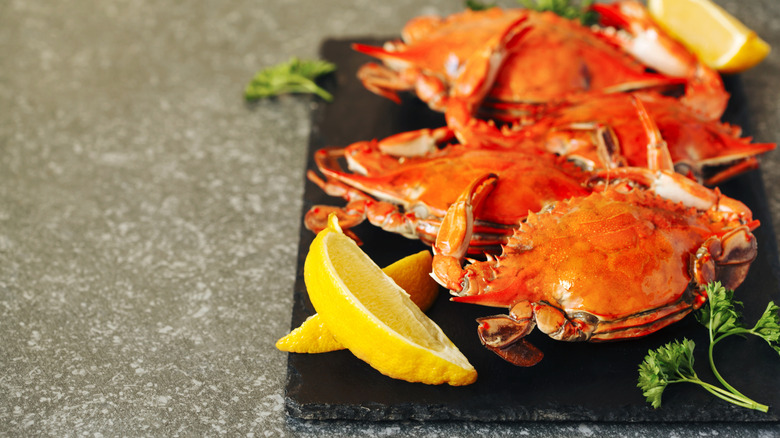 Red cooked crabs on a black slate with fresh lemon