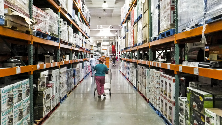 Person walking down an aisle at Costco with a shopping cart