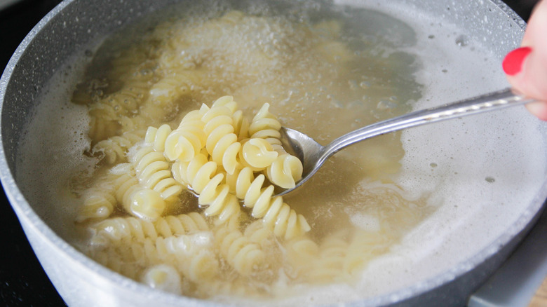 Stirring a pot of pasta with a metal spoon