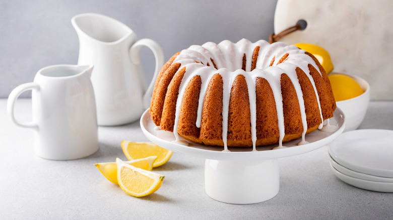 a lemon bundt cake with icing on a white cake stand