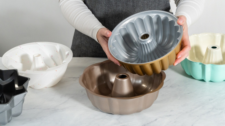 five different varieties of bundt pans, one held in woman's hands