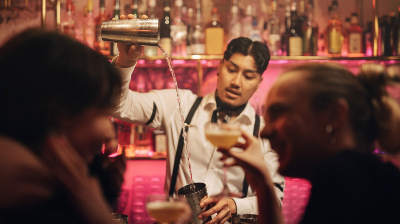 Bartender pouring cocktail from one shaker to another