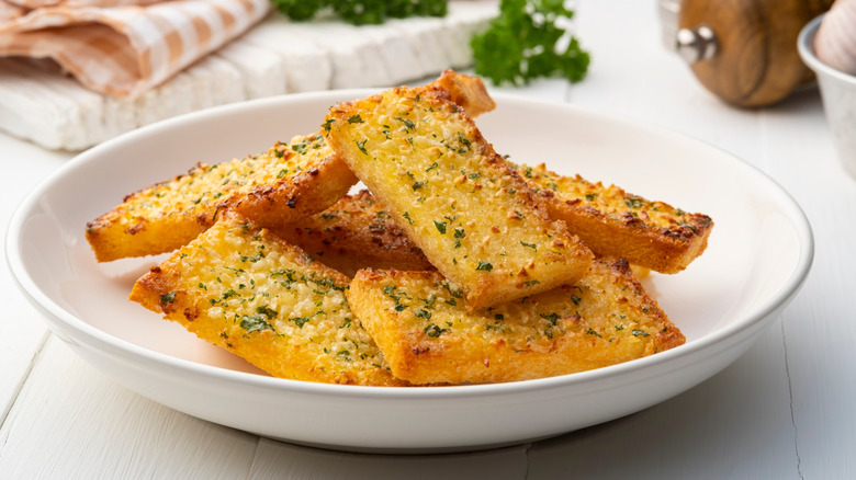 Multiple slices of garlic bread in white bowl