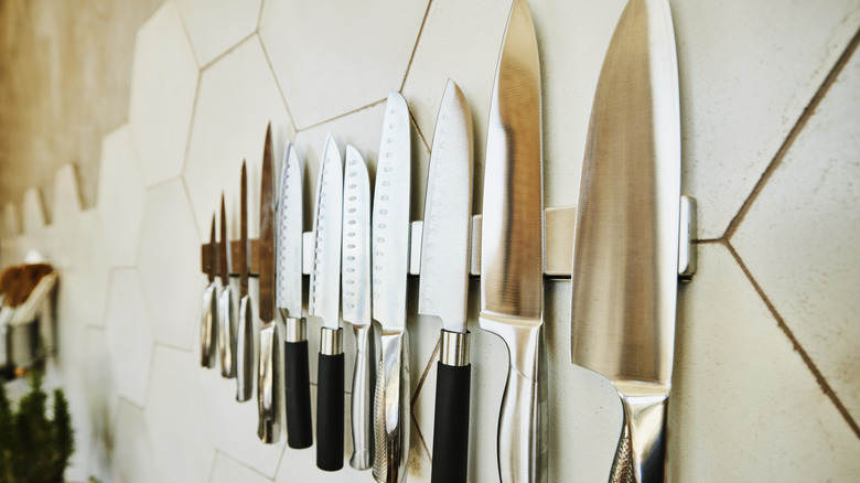 A set of knives on a magnetic strip on the wall