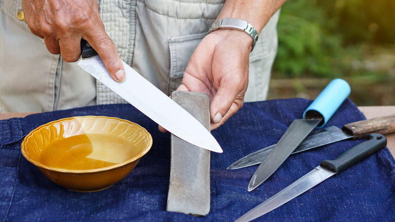 A man sharpening a knife against a stone