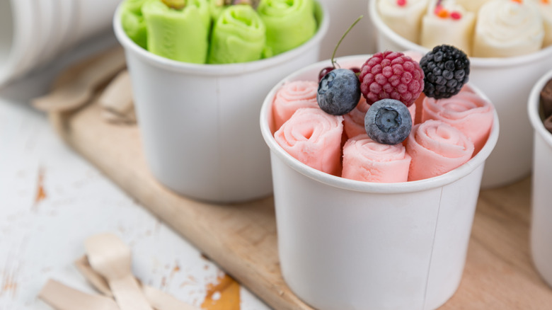 Rolled ice cream in white cups topped with frozen berries