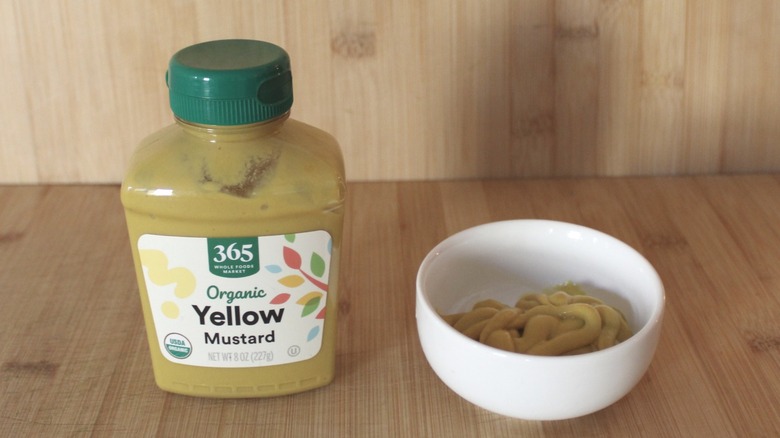 A bottle of 365 organic yellow mustard on a wood background