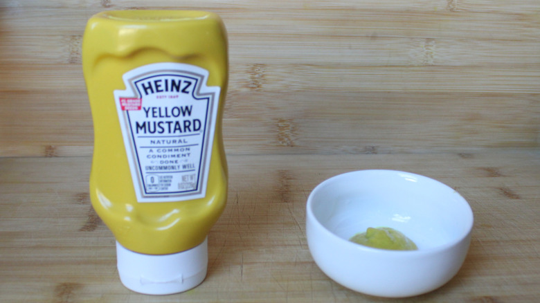 A bottle of Heinz yellow mustard on a wood background