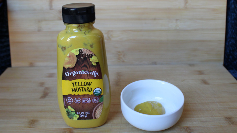 A bottle of Organicville yellow mustard on a wood background