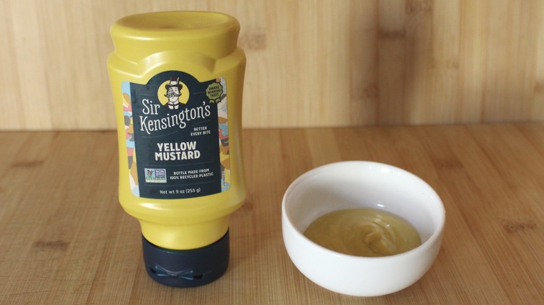 A bottle of Sir Kensington's yellow mustard on a wooden backdrop