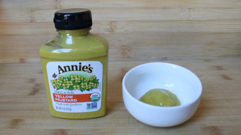 A bottle of Annie's organic yellow mustard on a wood background